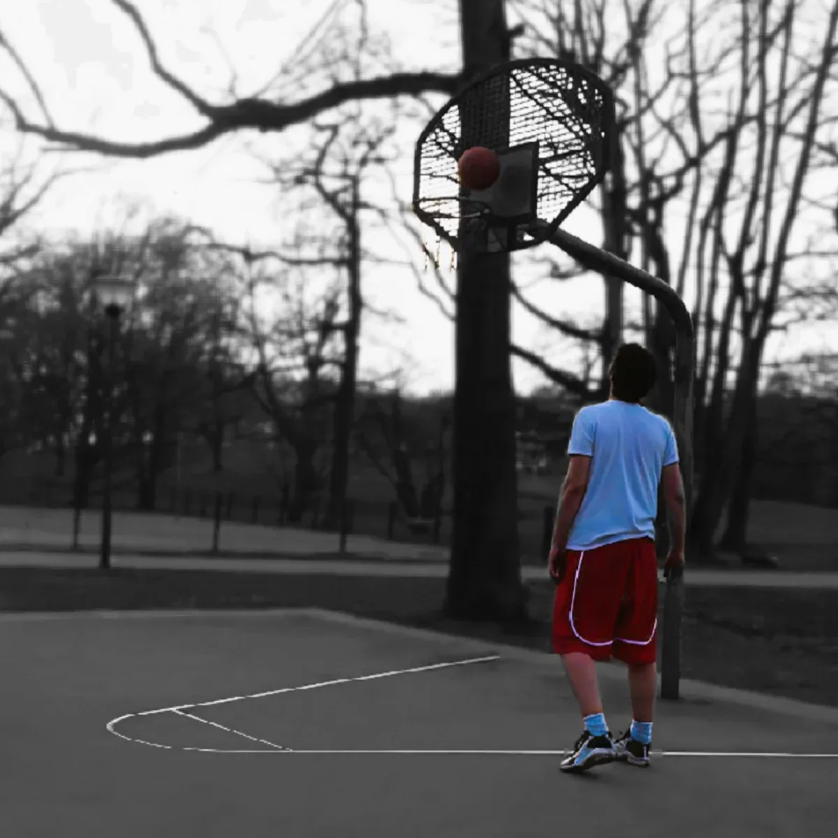 Mann wirft in der Abenddämmerung allein auf einem Basketballplatz auf den Korb